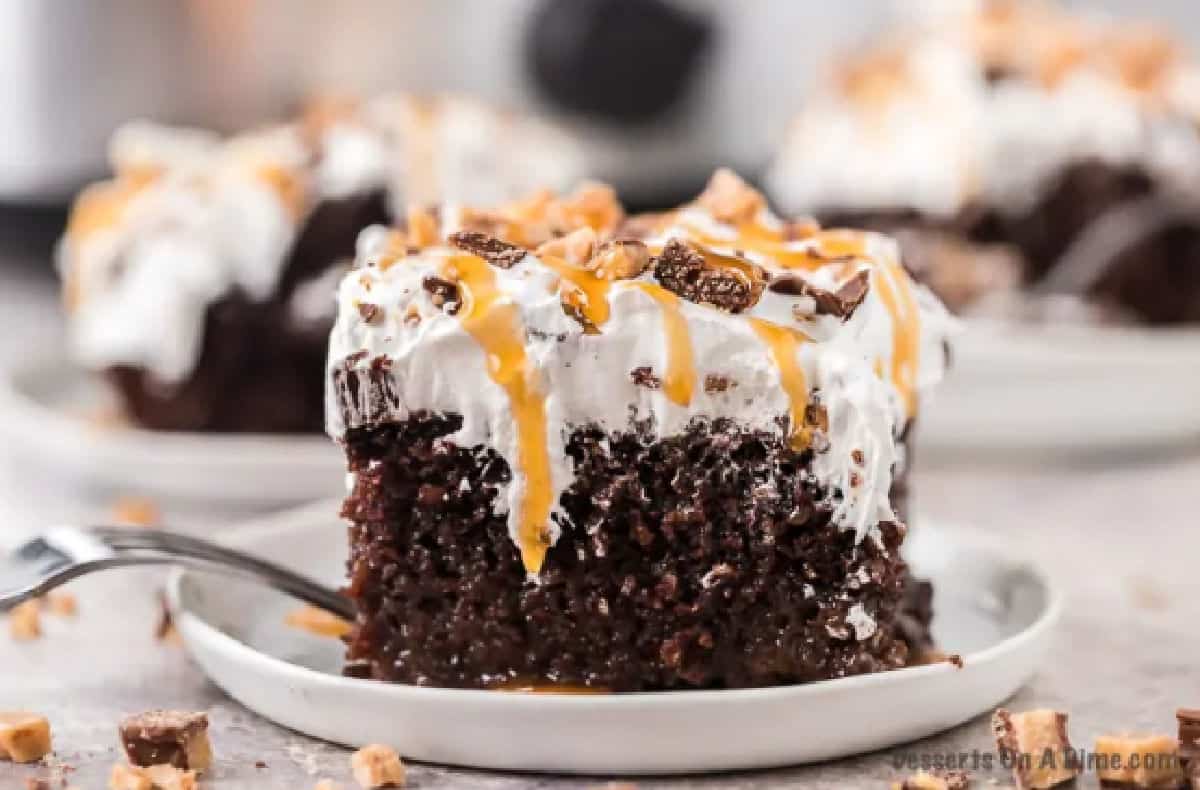 Better than sex cake cut into a square on a white plate.