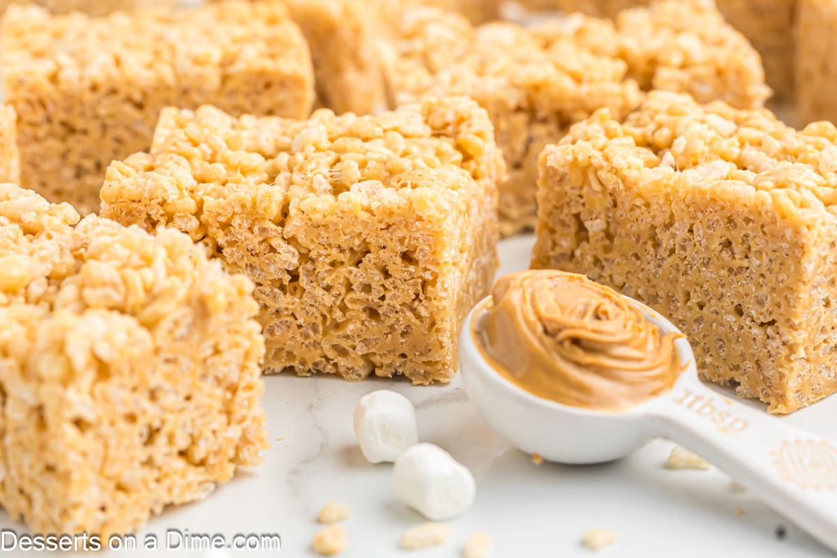 Squares of Peanut Butter Rice Krispie treats with a scoop of peanut butter.