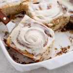 Homemade cinnamon rolls being served out of a casserole dish.