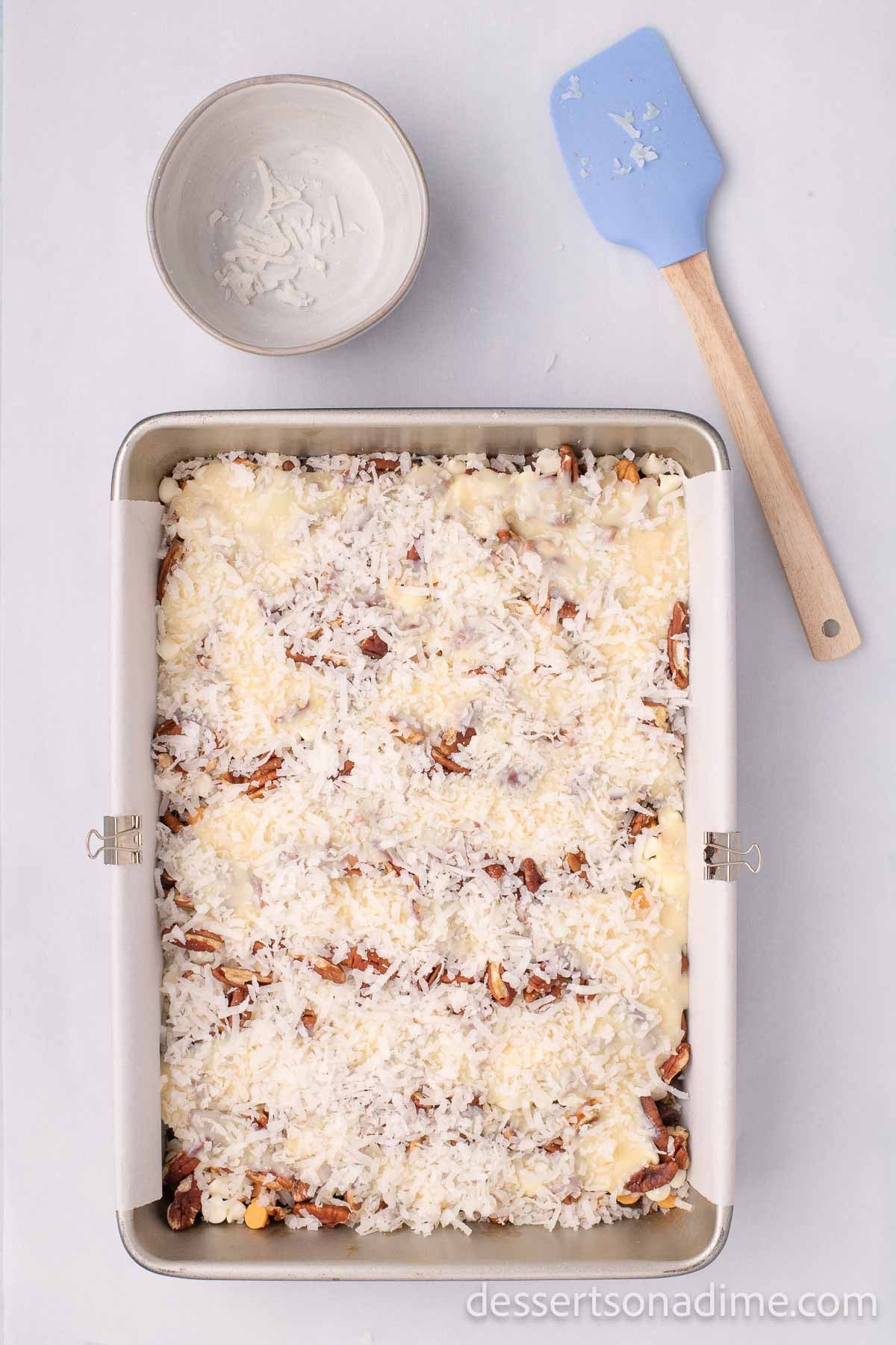 The shredded coconut sprinkled on top and gently pressed down into the other layers.  