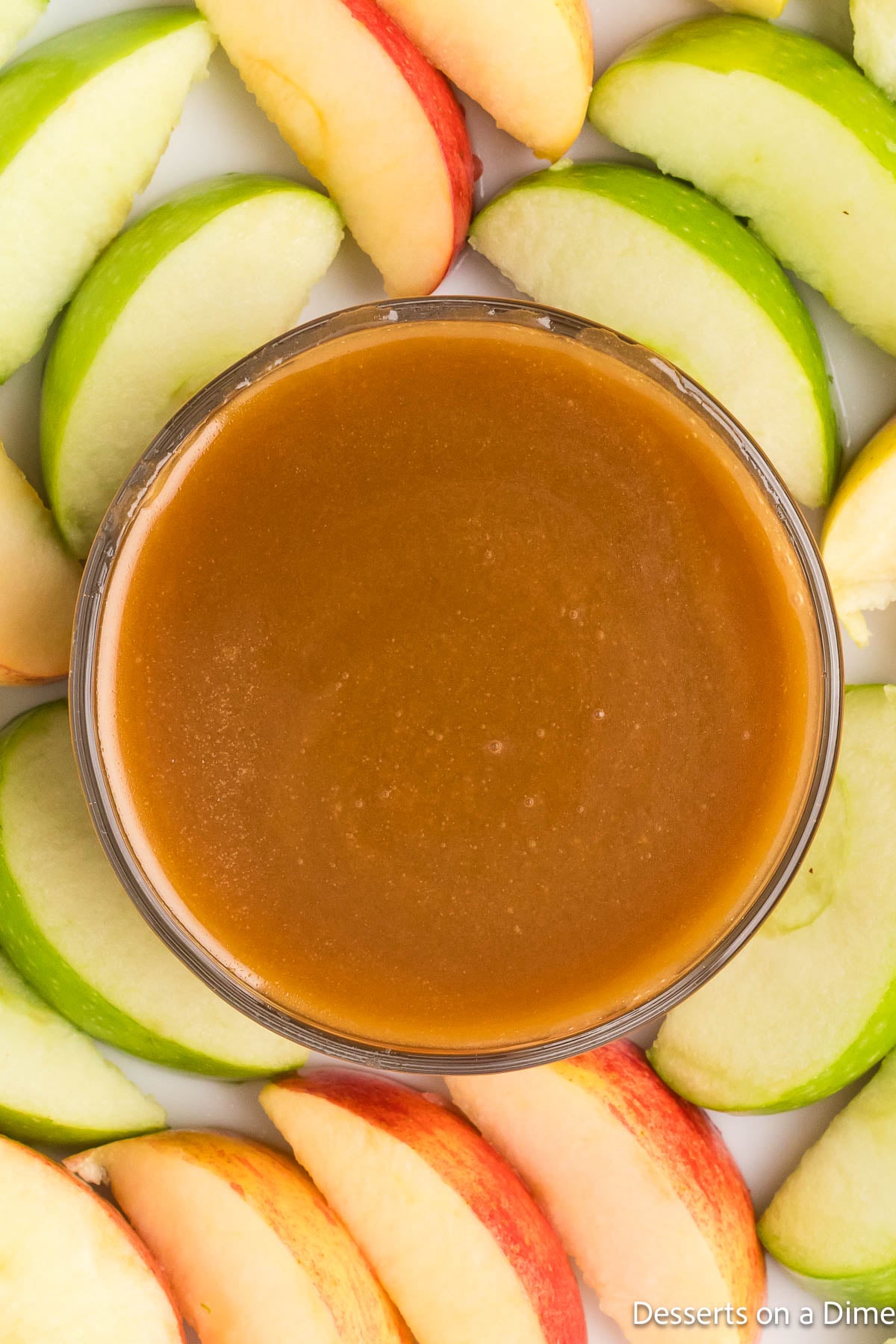 Caramel sauce in a bowl surrounded by apple slices. 