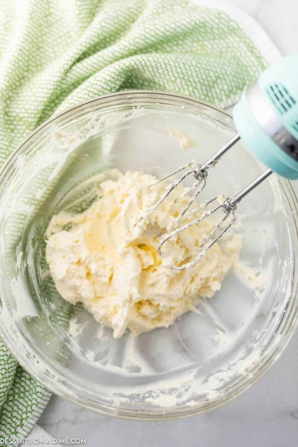 Cream cheese and butter combined in a bowl with a mixer. 