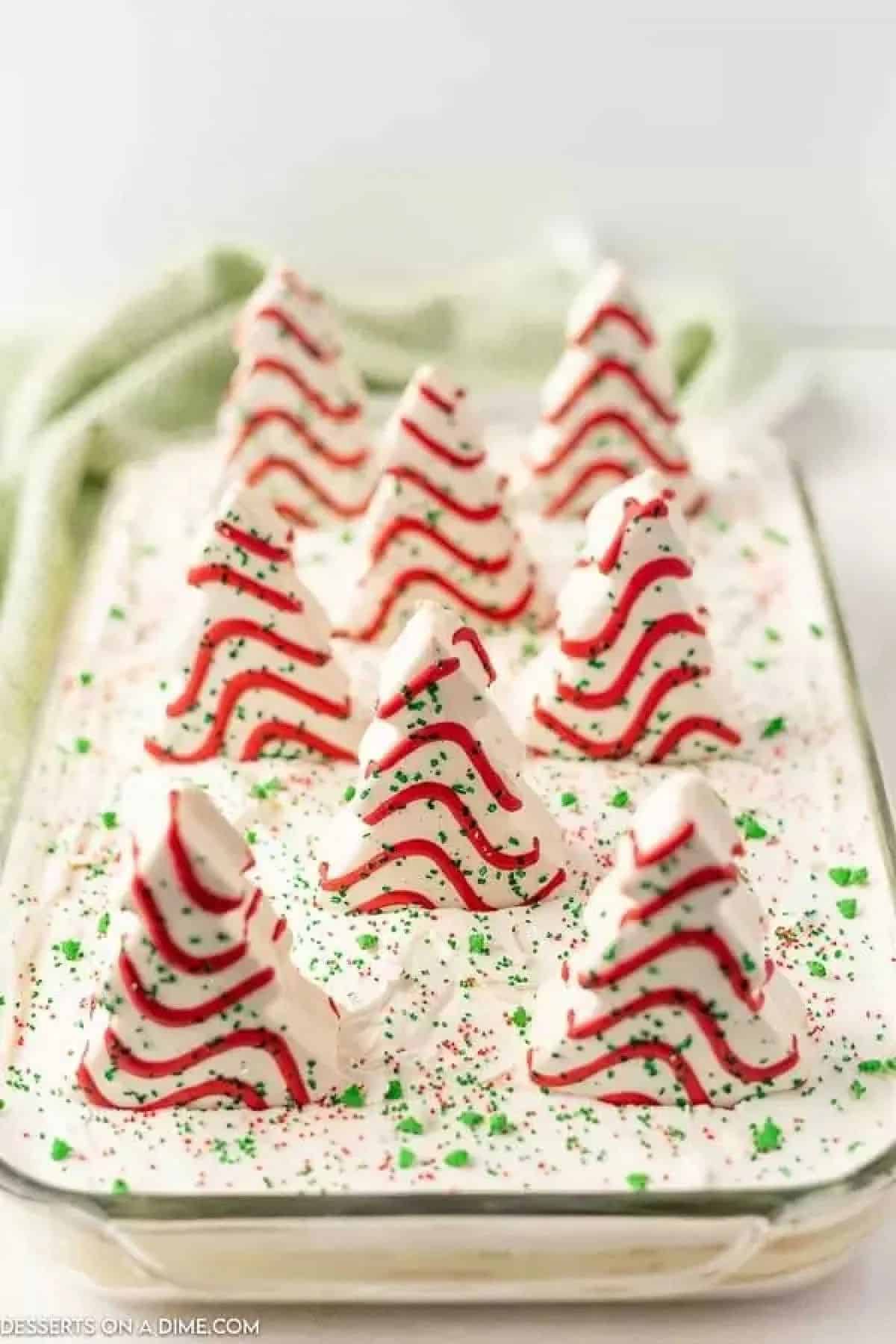 Little Debbie Christmas trees placed on top of baking dish with green sprinkles. 