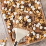 Smores poke cake topped with marshmallows, chocolate and graham crackers.