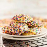 A plate of colorful sprinkles cookies on a cooling rack.
