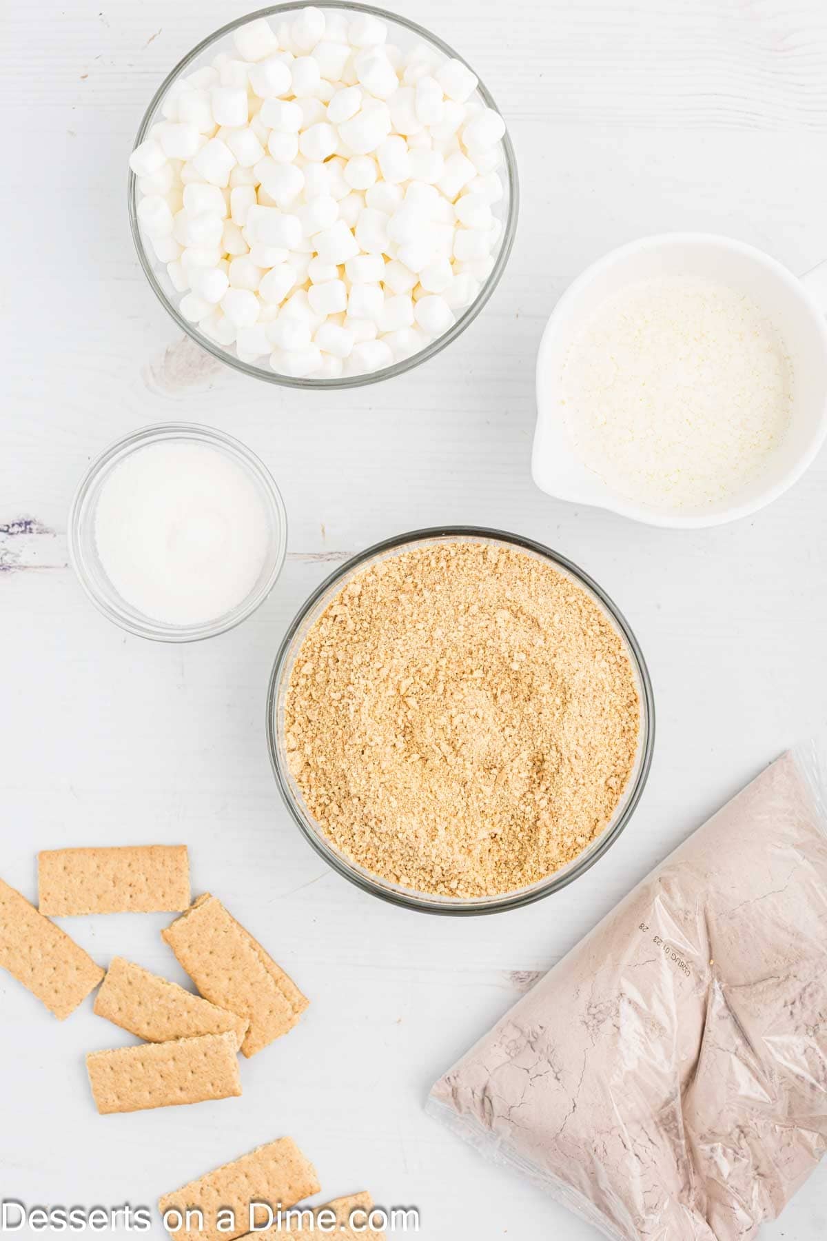 Ingredients for s'mores brownies - graham cracker crumbs, butter, brownie box mix, marshmallows, graham crackers.