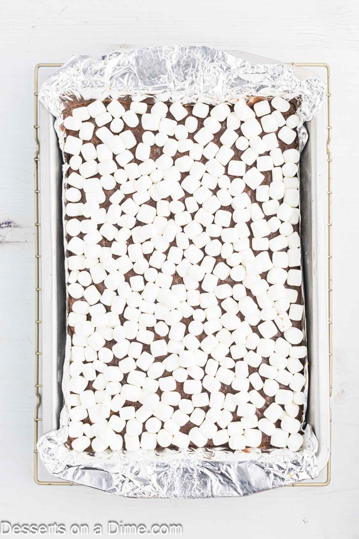 Mini marshmallows sprinkled on brownies in pan.