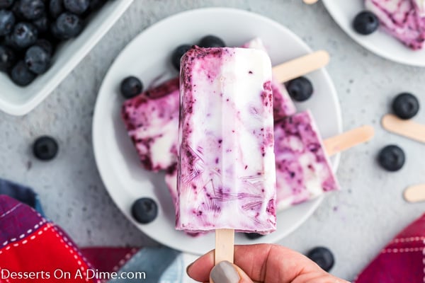 a person holding blueberry popsicles