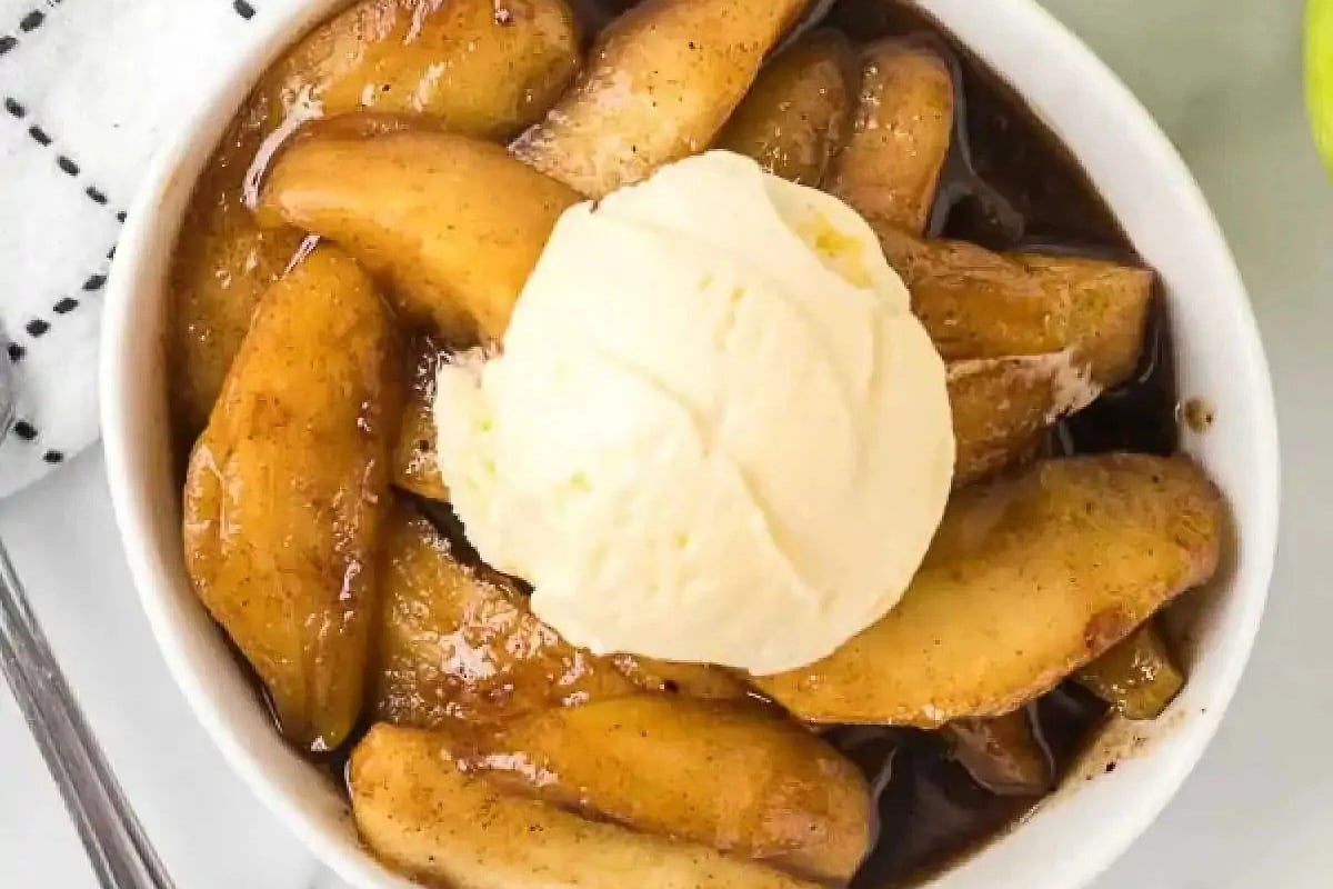 Fried apples in a bowl topped with ice cream.