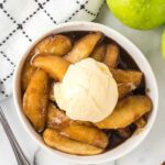 Fried apples in a bowl topped with ice cream.