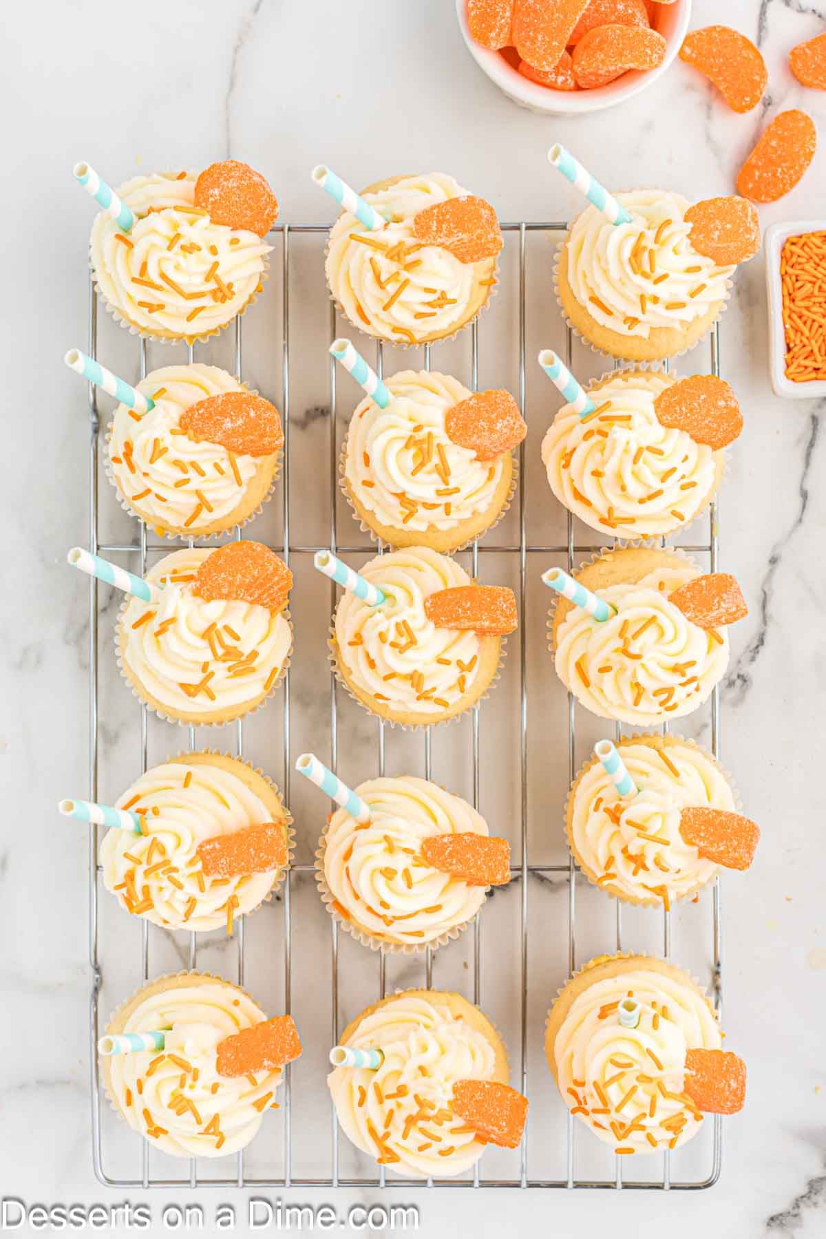 Cupcakes on wire rack with frosting and topping. 
