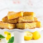 Close up image of Lemon squares stacked on a cake plate