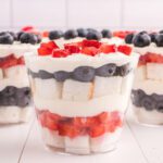 Close up image of layers of angel food cake, strawberries, blueberries and cream all in a mini cup.