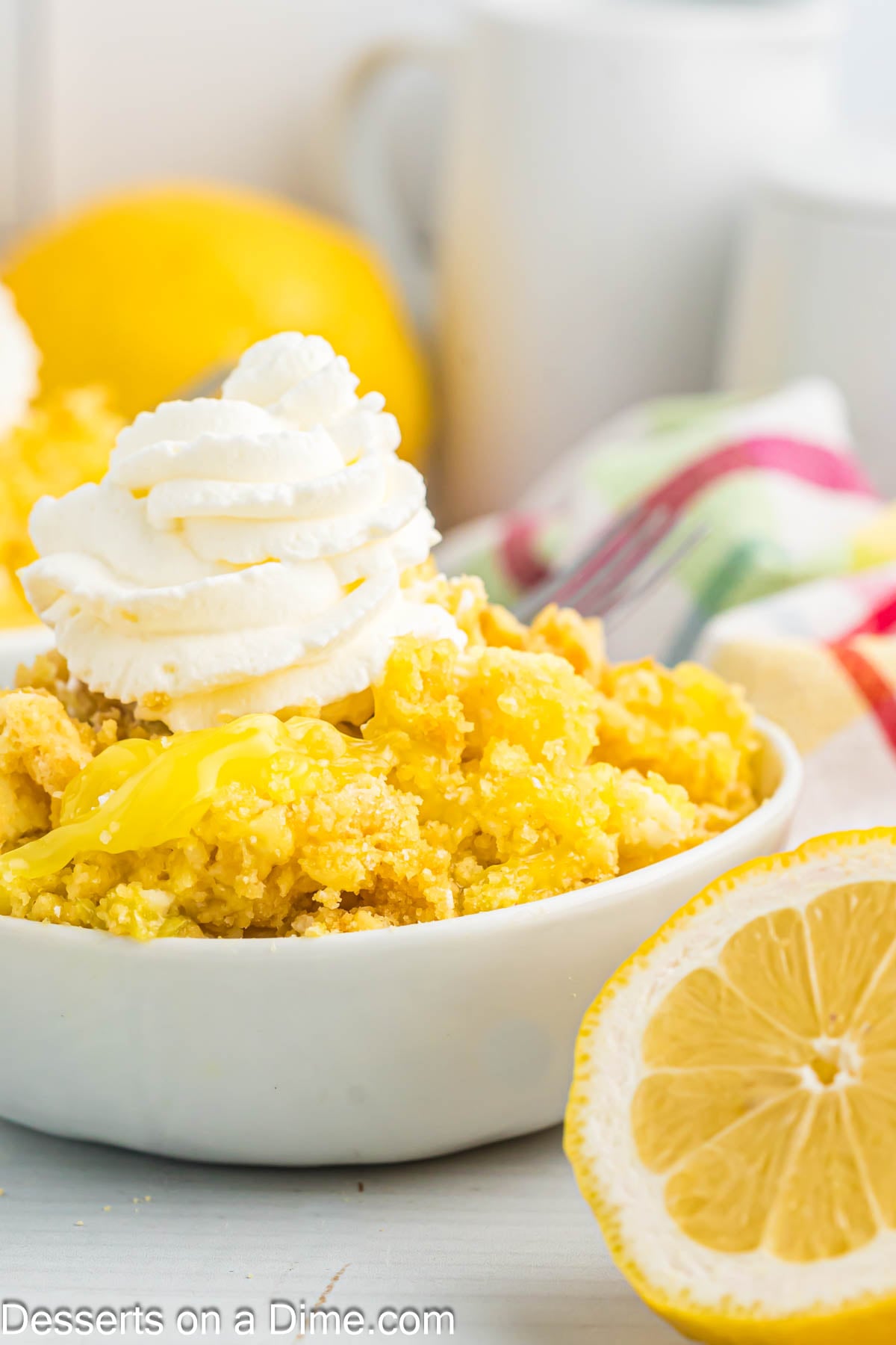 Serving of lemon dump cake topped with whipped cream in a bowl
