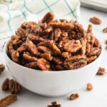 Sweet candied pecans in a white bowl, perfect for desserts and snacks.