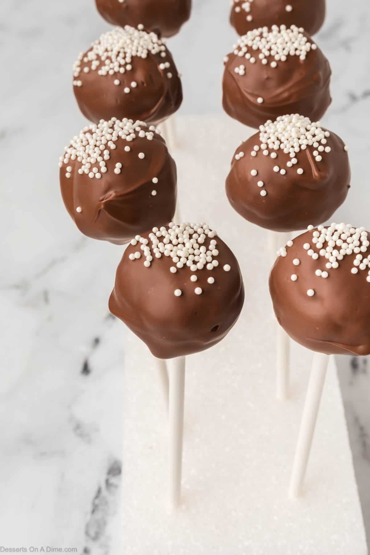Cake pops topped with sprinkles and inserted in stand.