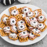 A plate of halloween pretzels with eyes and candy.