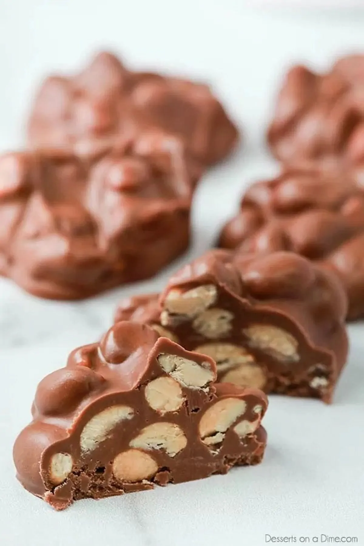 Crockpot Peanut Clusters Recipe is a simple dessert idea with only 5 ingredients. The crock pot does all the work and the results are tasty chocolate candy. Chocolate peanut Clusters cut in half
