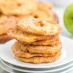 Golden fried apple rings with cinnamon sugar on white plate