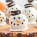 Snowman oreo balls on a wooden board.