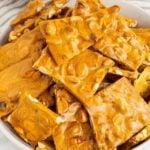 Close up of Peanut Brittle stacked on top of each other in a large white bowl.