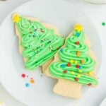 Christmas tree sugar cookies with frosting on a white plate.