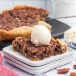 Buttermilk Pie with pecans and a scoop of vanilla ice cream on a white plate.