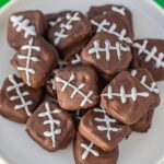 Chocolate covered footballs on a white plate.