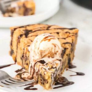 A slice of pizookie topped with ice cream and chocolate syrup
