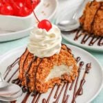 A dessert with whipped cream and cherries on a plate.