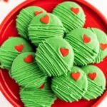 Grinch Oreo cookies on a red platter.