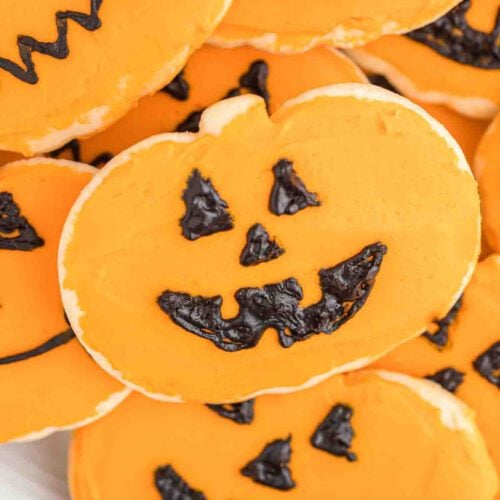 Halloween pumpkin cookies are decorated with black icing.