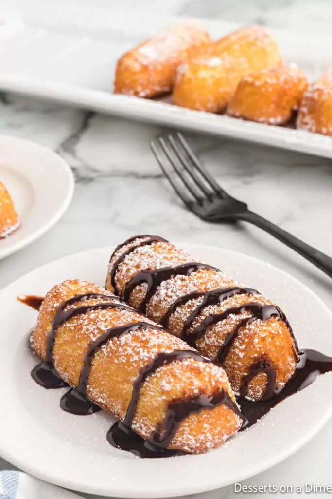 Fried twinkies on a plate drizzled with chocolate