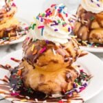 A stack of fried marshmallows with whipped cream and sprinkles.