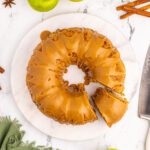 Apple Bundt Cake on a white platter being sliced.