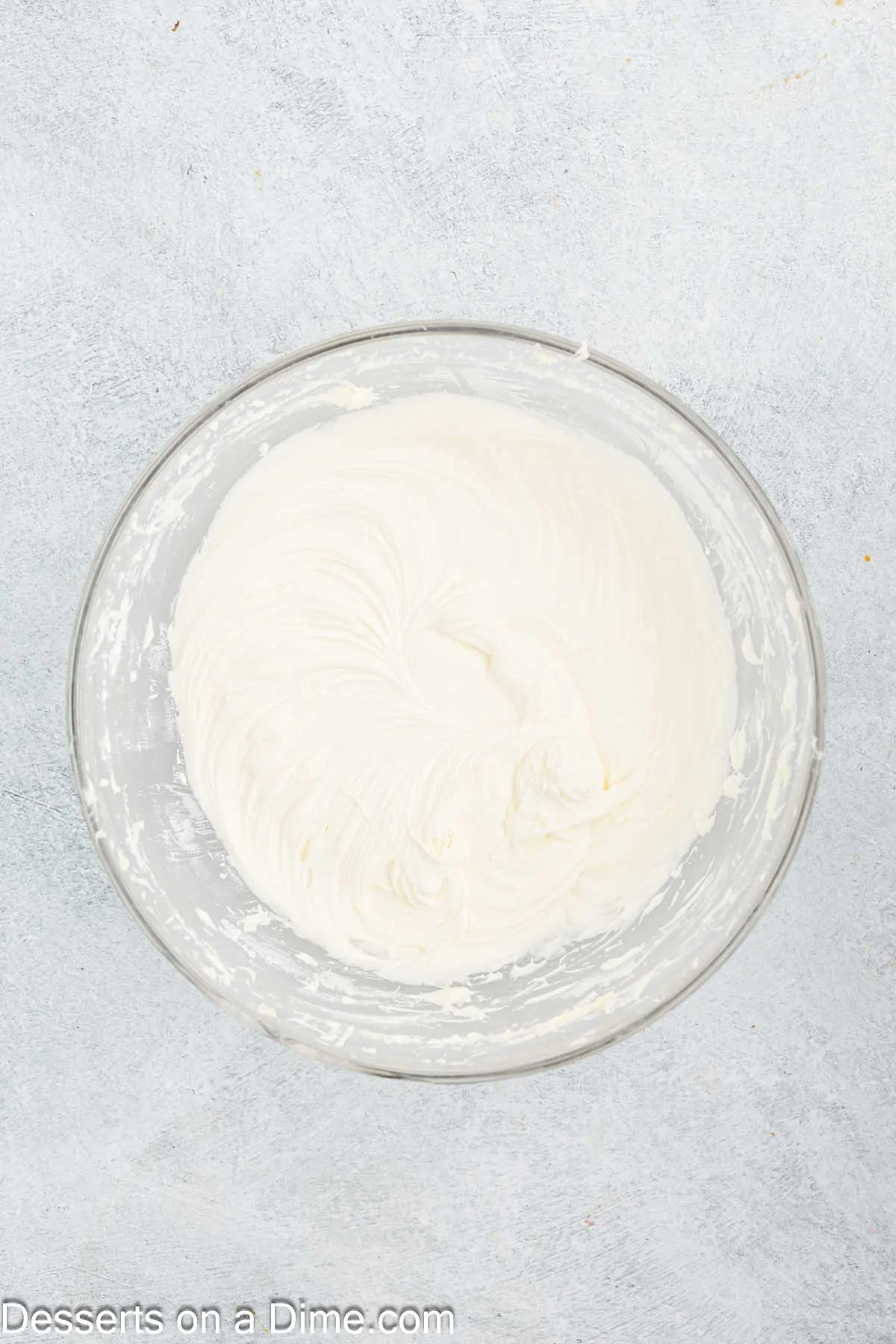 Powdered sugar mixed into bowl of frosting.