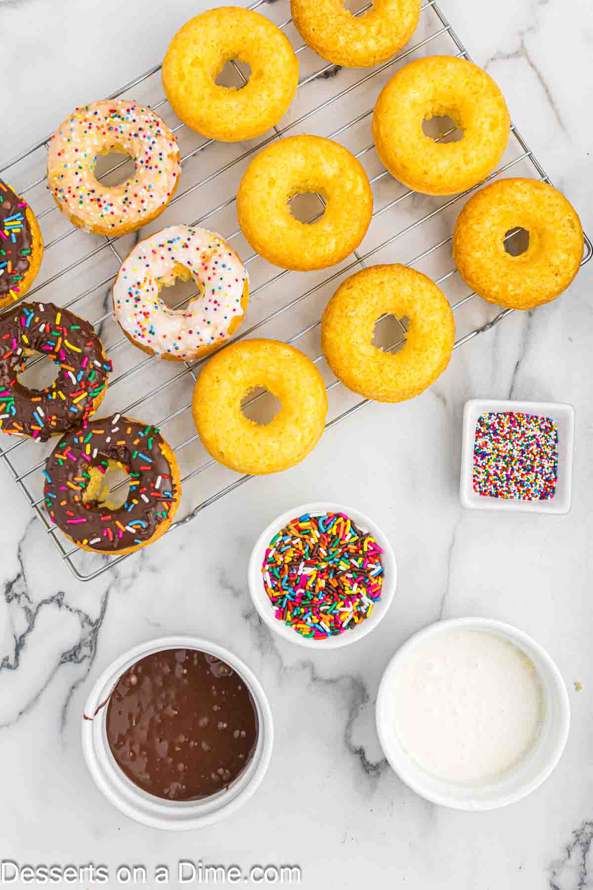 Donuts with glaze and sprinkles on wire rack.