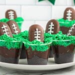 Chocolate football dessert cups with green frosting for game day.
