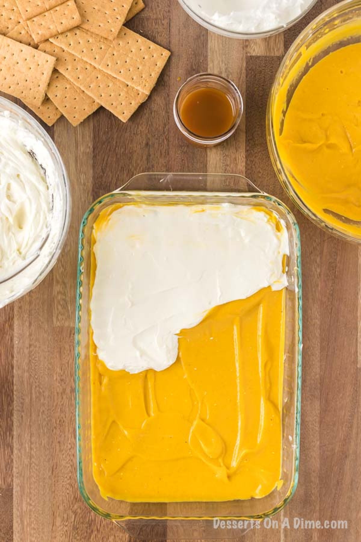 Half of the cream cheese mixture being spread on top of the layer of the pumpkin mixture.  