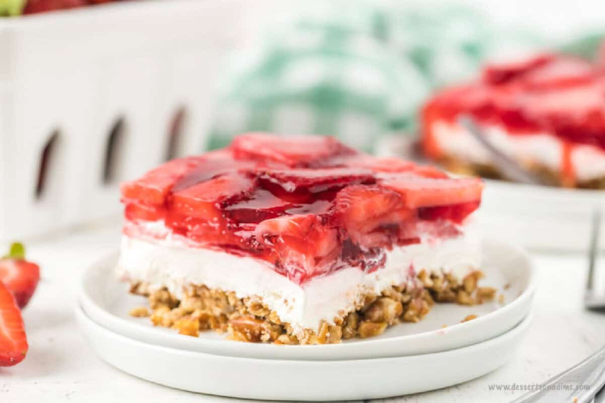 Strawberry pretzel dessert recipe is the perfect combination of salty and sweet. The creamy filling is so decadent and the strawberry topping is delicious. Strawberry Pretzel Dessert sliced and served on a white plate.