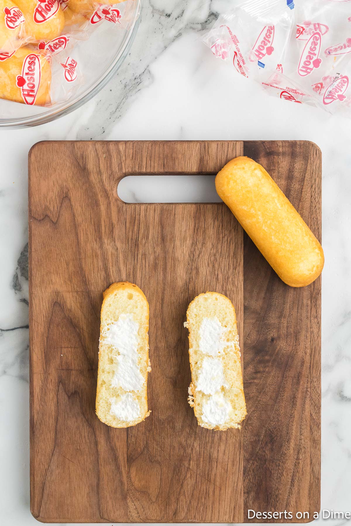 Cutting board with twinkies cut in half.