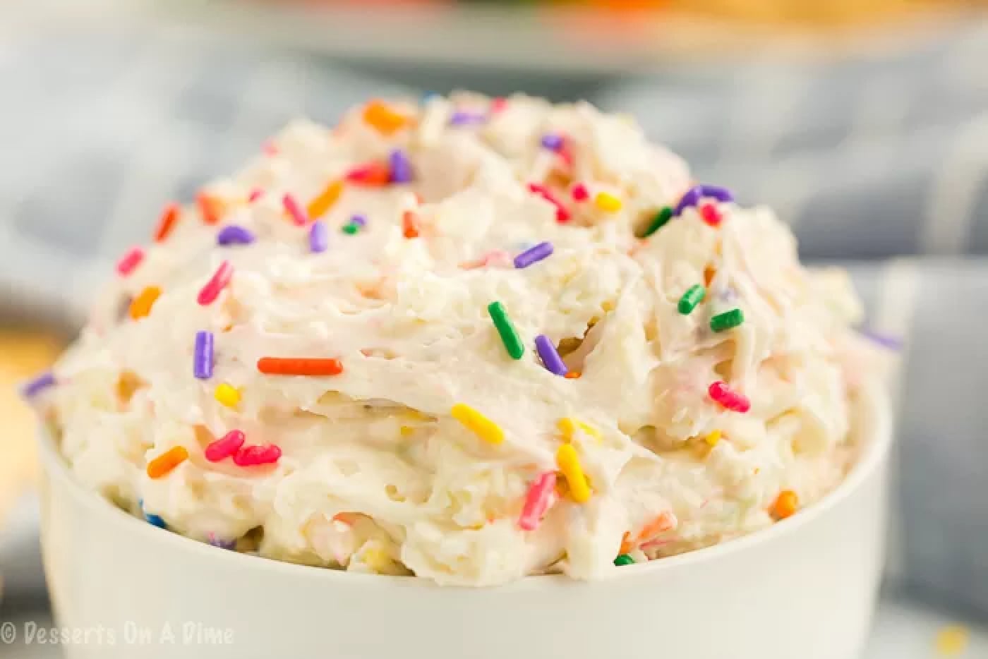 Cake batter dip in a bowl and topped with sprinkles. 