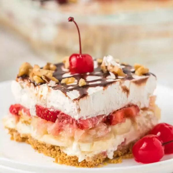 Banana Split Cake sliced on a plate and topped with a cherry.