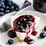 Blueberry cheesecake with a slice of blueberry cheesecake on a white plate.