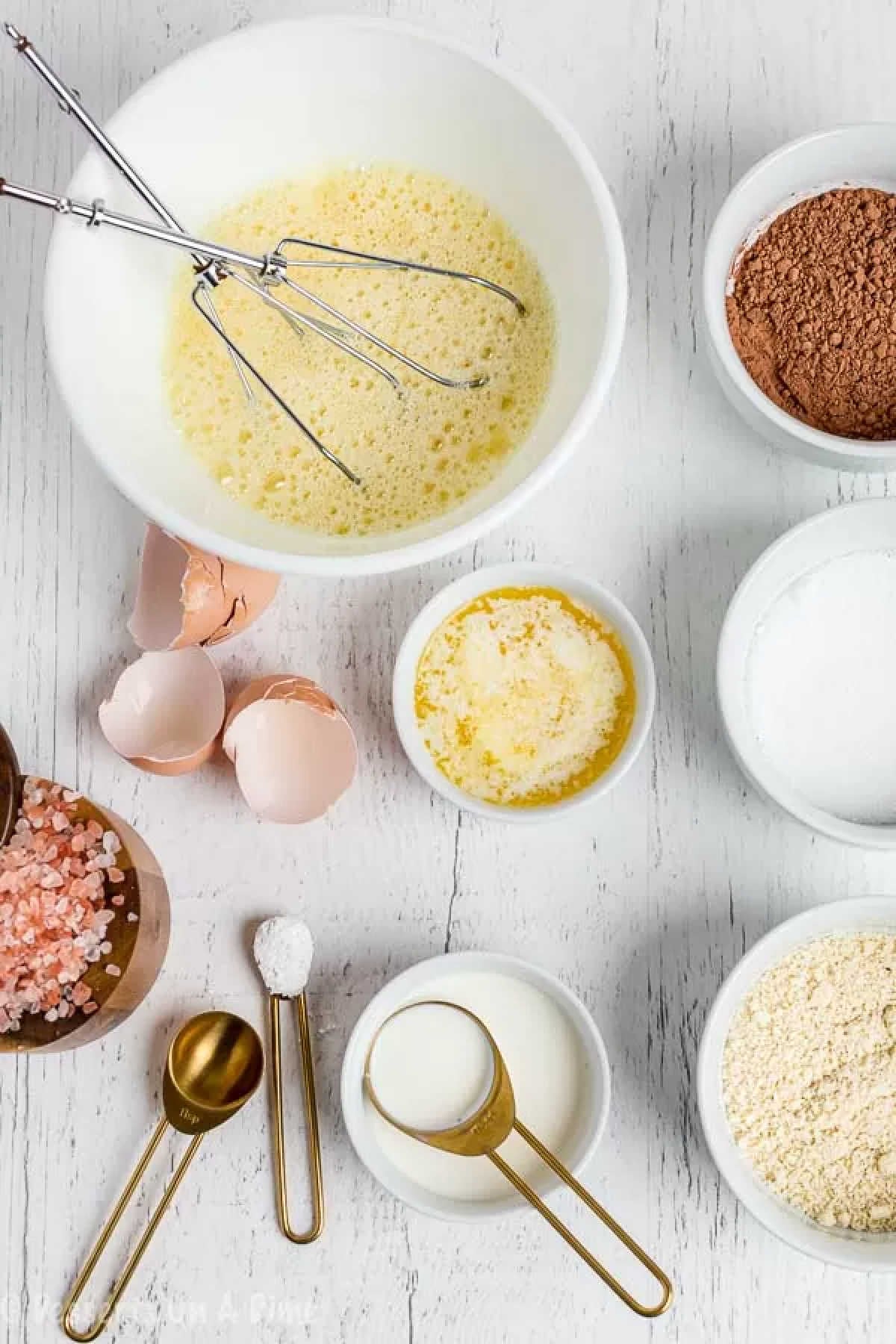 Bowl of melted butter beside a bowl of eggs. 