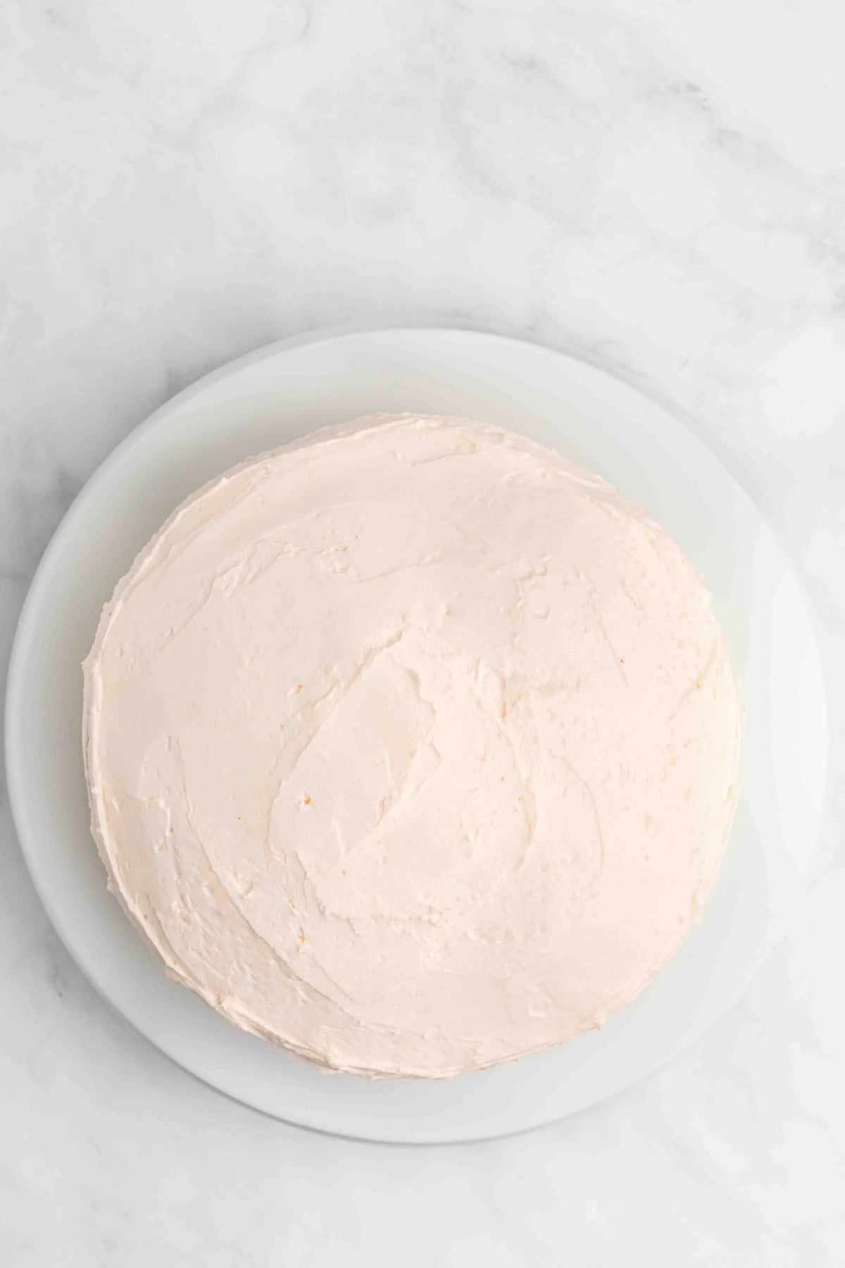 Cake on platter being frosted. 