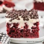Red Velvet poke cake topped with chocolate chips and served on a plate.
