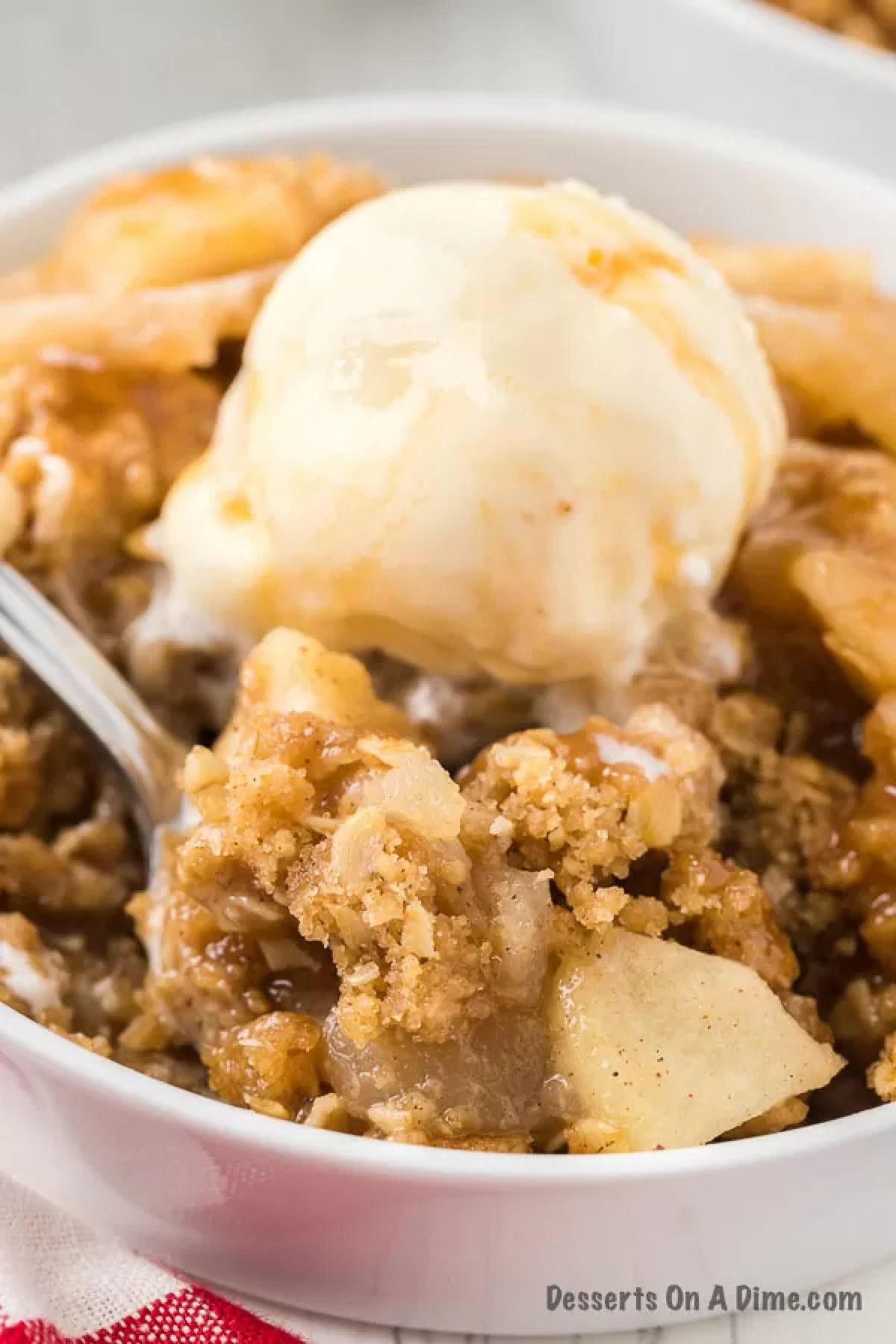 Apple crisp in a bowl topped with ice cream. 