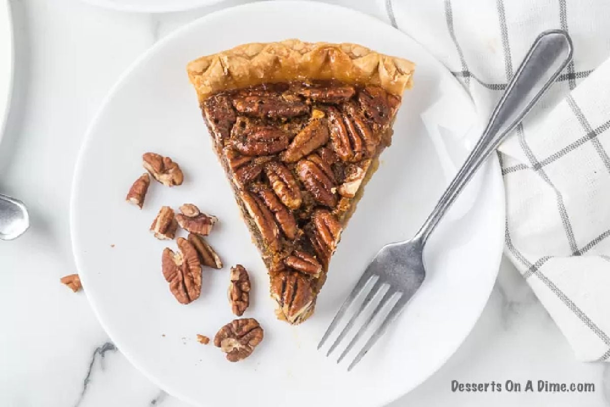 Slice of pecan pie on a white plate.