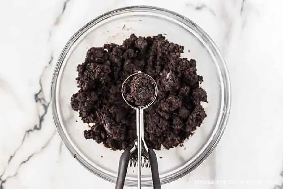 Bowl of crushed oreo cookies combined with cream cheese. 
